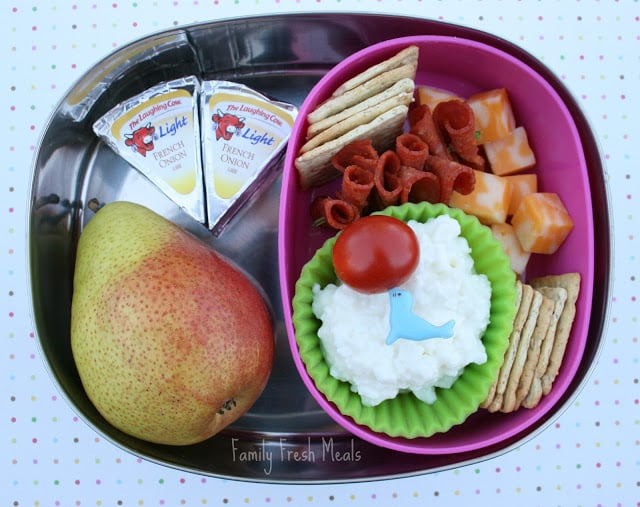 Top down image of a lunch box with a pear, cheese, crackers and pepperoni