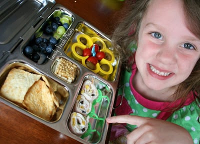 Child sitting at a table with flower themed lunchbox