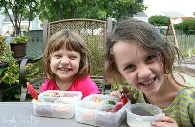 2 children sitting and smiling with Panda Bear lunchboxes