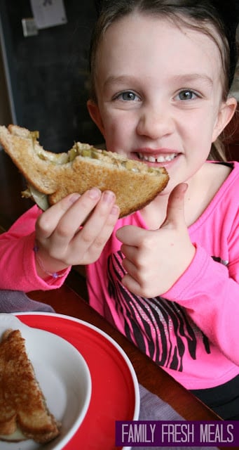 girl holding Green Bean Casserole Grilled Cheese sandwich, giving a thumbs up