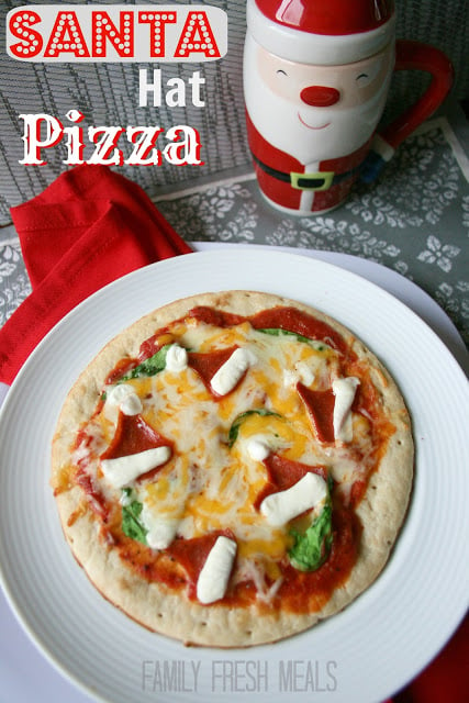 Santa Hat Christmas Pizza on a white plate with a Santa cup in the background