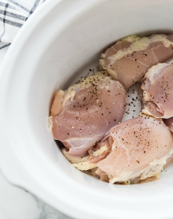 Chicken placed in bottom of crockpot and topped with seasoning