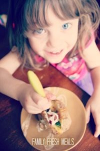 child sitting at a table eating a crockpot baked potato