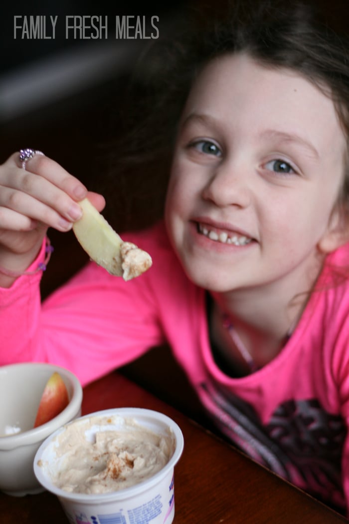 Child eating yogurt dip with apple slices