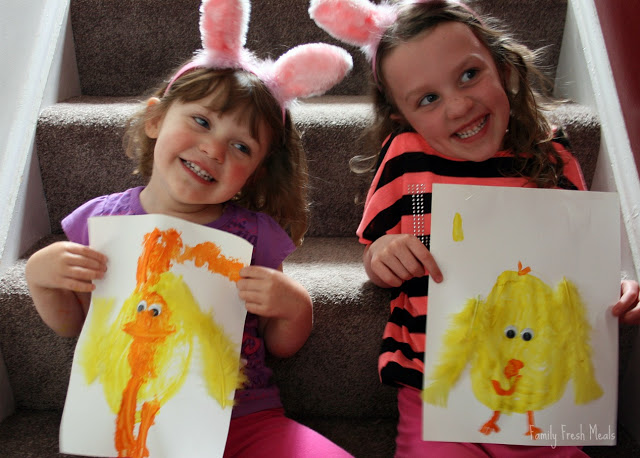 2 children sitting on stairs with bunny ears, holding spring art craft