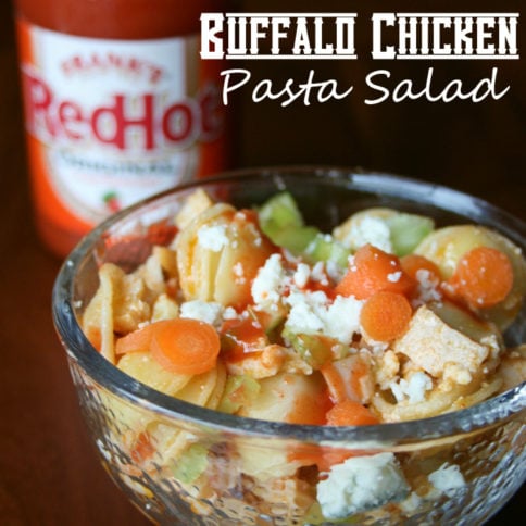 Buffalo Chicken Pasta Salad in a small glass bowl with a bottle of hot sauce in background