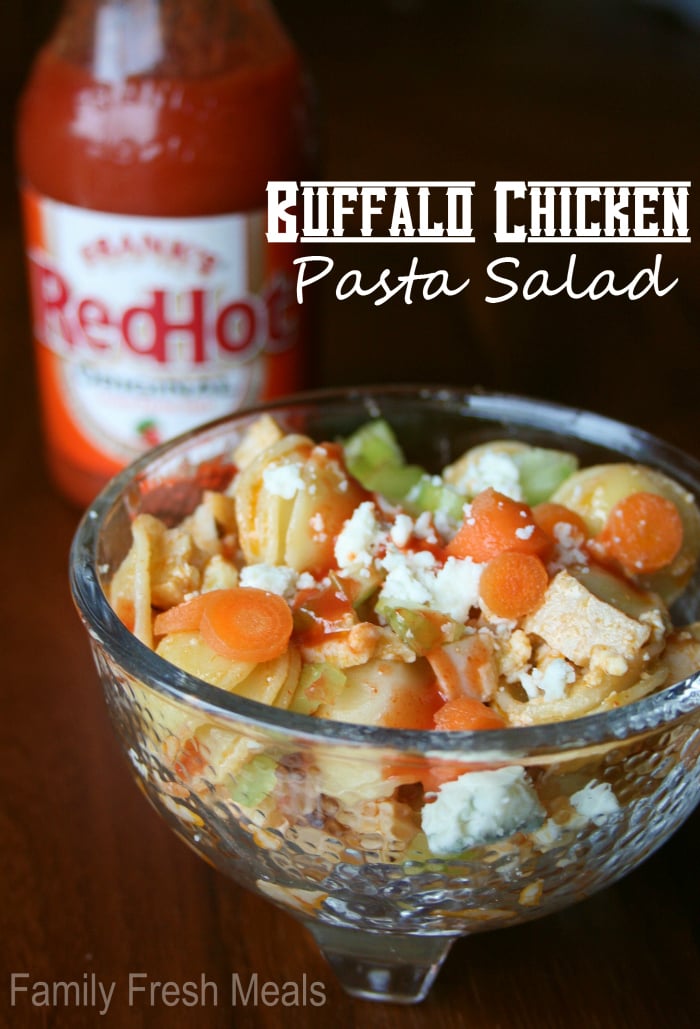 Buffalo Chicken Pasta Salad in a small glass bowl with a bottle of hot sauce in background