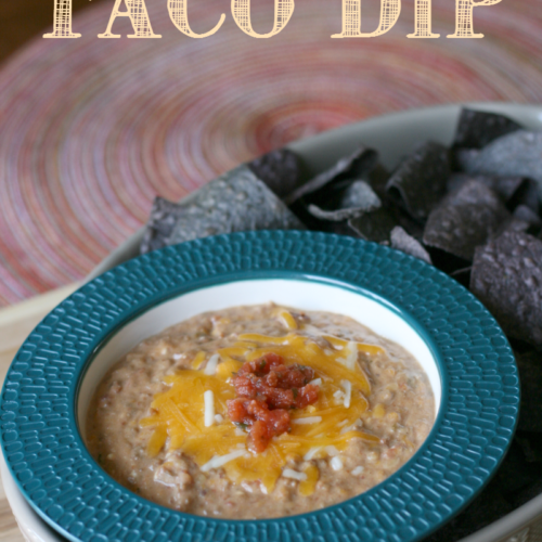 Cheesy Crockpot Taco Dip served in a blue bowl with a side of chips