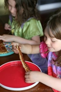2 children sitting at table with bacon pancakes