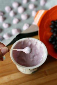 dipping a blueberries into yogurt with a toothpick