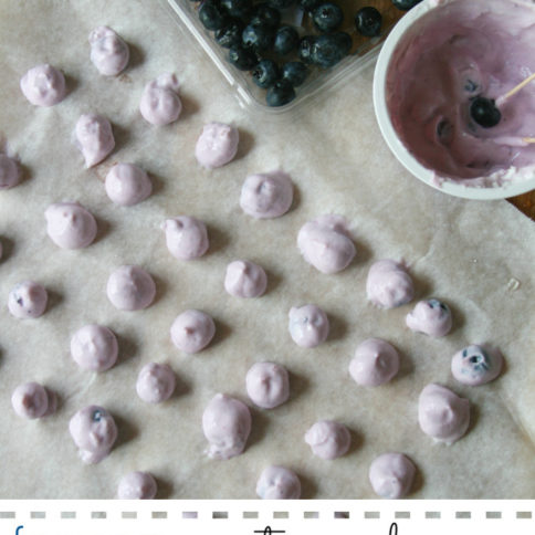 Frozen yogurt covered blueberries on a baking sheet