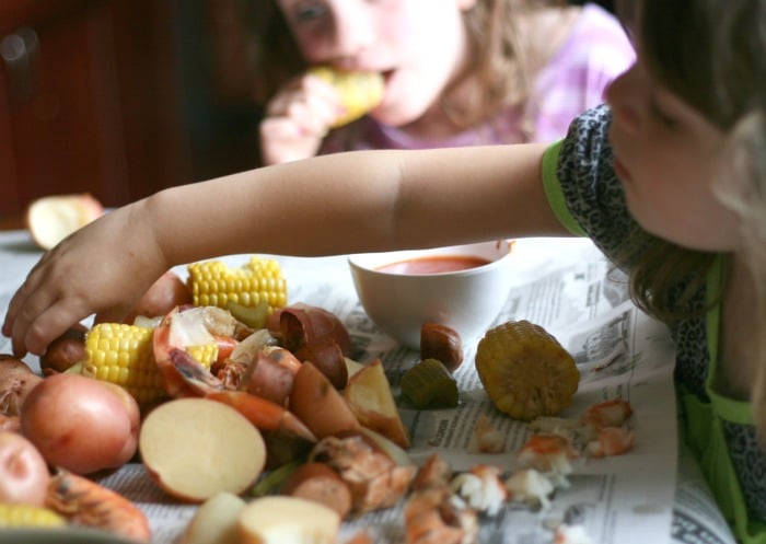 two children sitting at table, eating Crockpot Low Country Boil 