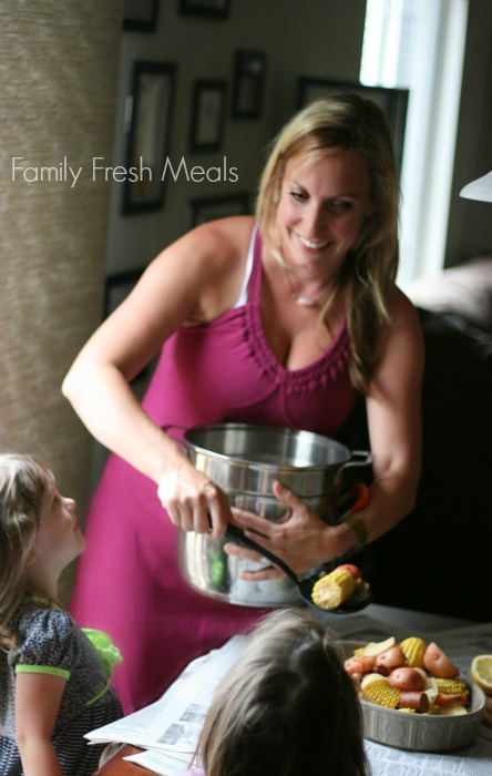 Woman serving crockpot low country boil to tow children