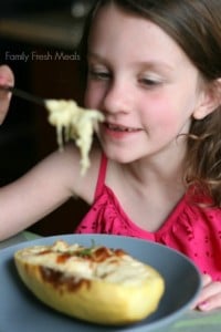 Child sitting at a table eating the Cheesy Spaghetti Squash Casserole