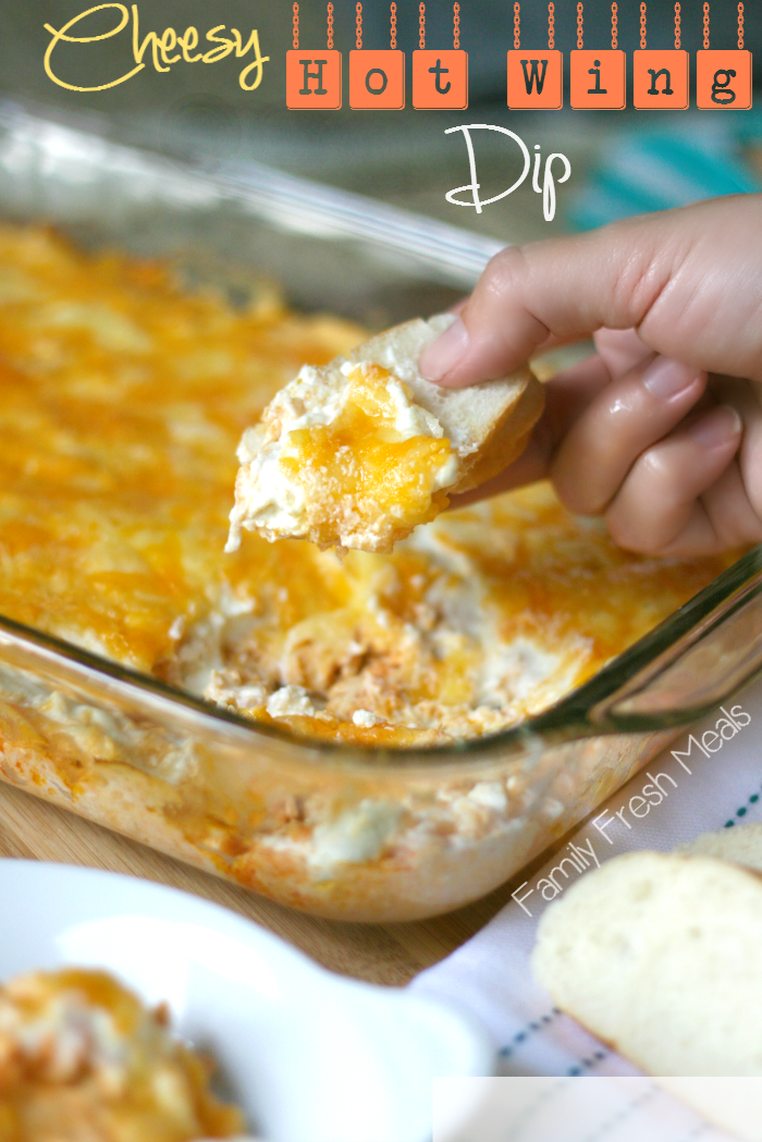 Hand scooping up Cheesy Hot Wing Dip with a slice of bread