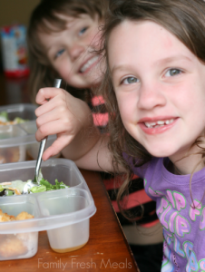 Two children sitting with lunchboxes