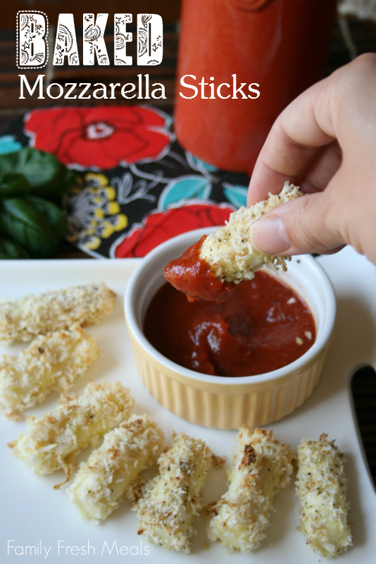 Mozzarella sticks on a white plate, with a hand dipping a baking mozzarella stick in red sauce