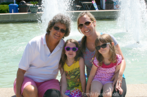 2 women and 2 children sitting in front of a water fountain