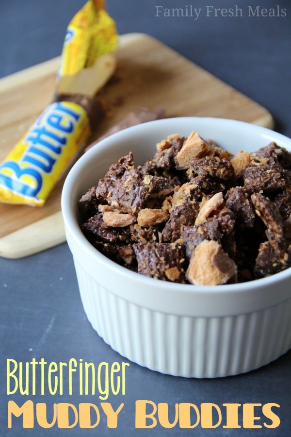 Butterfinger Muddy Buddies Recipe served in a white dish, with an open butterfinger candy car in the background