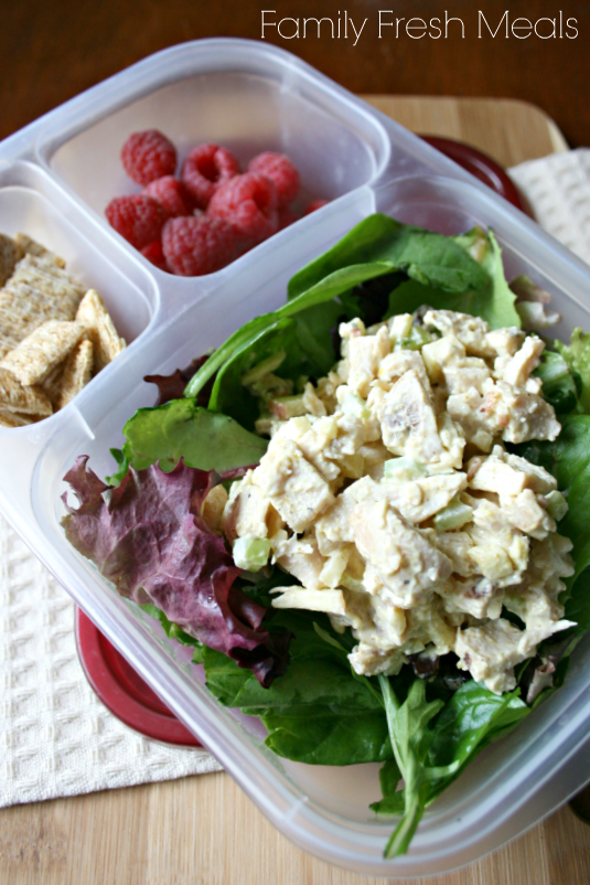 Curried chicken salad on a bed of lettuce, raspberries and some mini wheat cracker - packed in a lunchbox