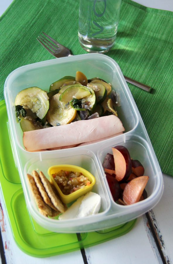 lunchbox packed with roasted vegetables, rolled lunchmeat, olive spread and fruit