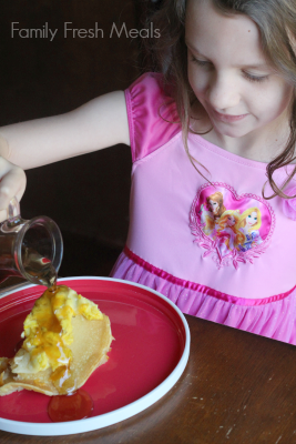 Child pouring syrup over breakfast casserole 