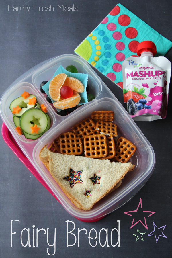 Top down image of a school lunchbox - half sandwich, cucumbers, pretzels, orange slices and gummies