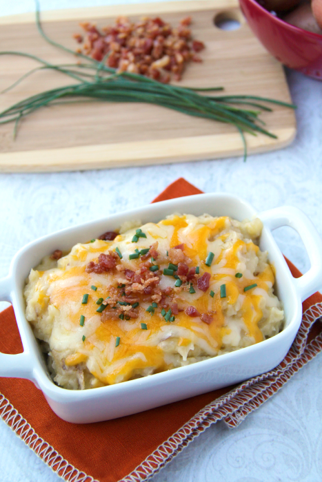 Cheesy Crockpot Mashed Potatoes served in a white bowl, topped with chives and bacon