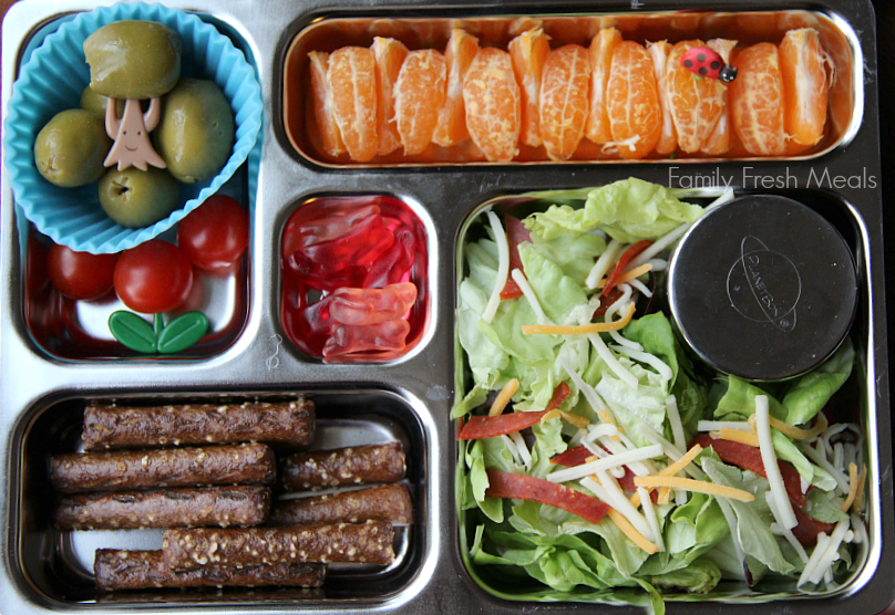 salad with a container of dressing, oranges, pumpernickel pretzels, cherry tomatoes, olives and some fruit snack bunnies for dessert. Packed in a metal lunchbox