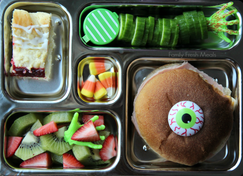 There is a turkey and cheese sandwich,  cucumbers and a container of dip, small piece of leftover coffee cake, fresh strawberries & kiwi and some candy corn.  Packed in a Planetbox lunchbox