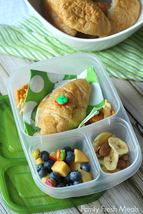 deli sandwich on a croissant,  bunny crackers,  fresh blueberries and peach, and  an almond/banana chip mix - packed in a lunchbox