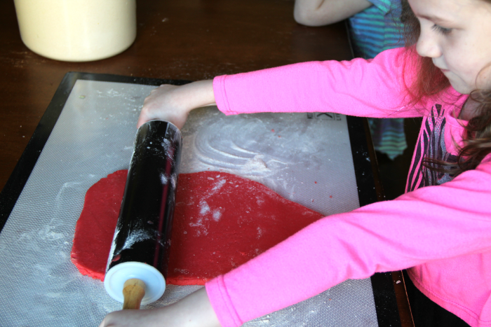 a child rolling out read dough with rolling pin