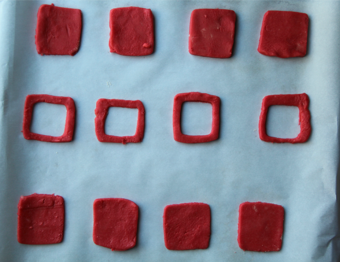 red dough square cut-outs on parchment paper