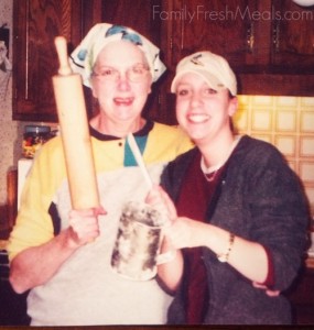 2 woman standing together holding a rolling pin and a sugar sifter