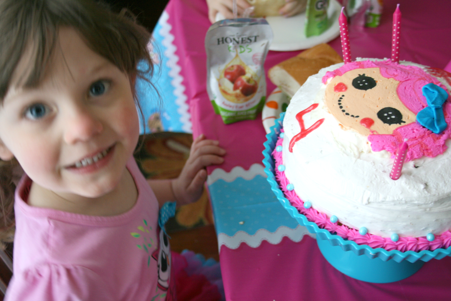 Child sitting at a table with a Lalaloopsy Cake