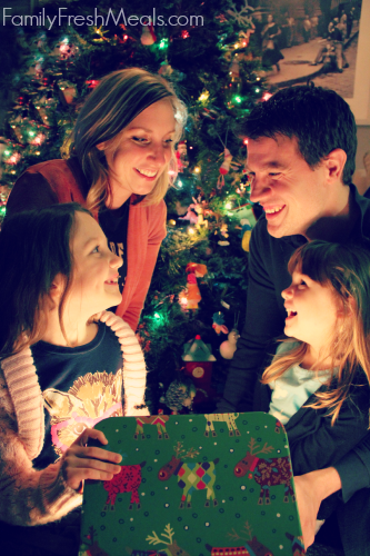 Family gathered around a present smiling