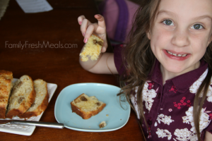 Child sitting at table eating a piece of bread