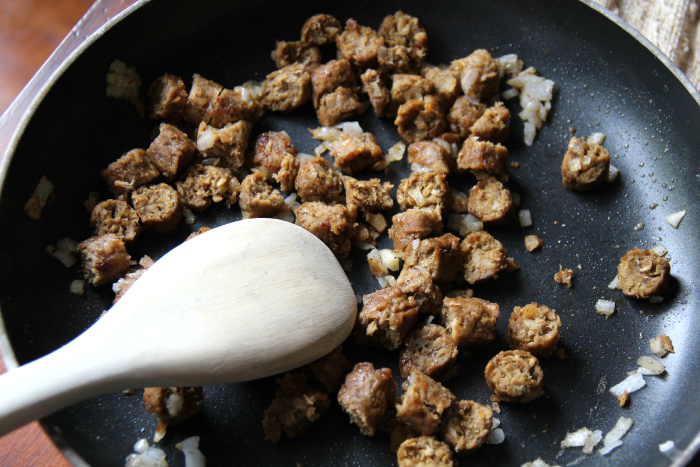 sausage pieces cooking in a pan with diced onion