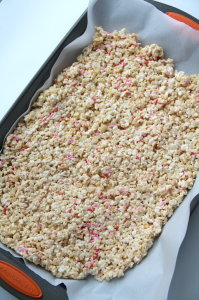 Rice krispy treats pushed into a parchment paper lined pan