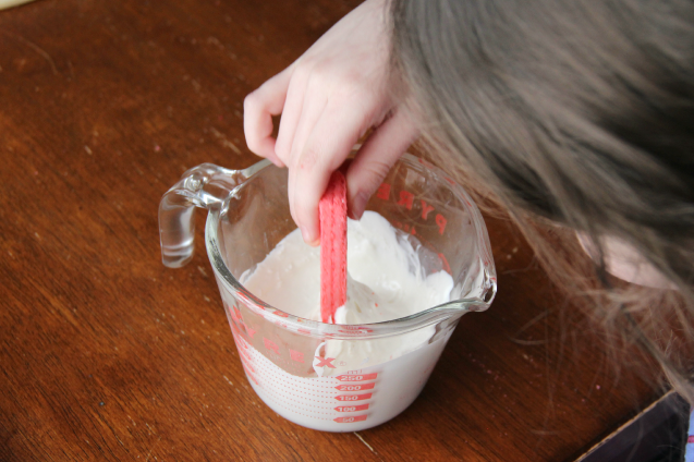 Child dipping pink wafer cookie into candy melts