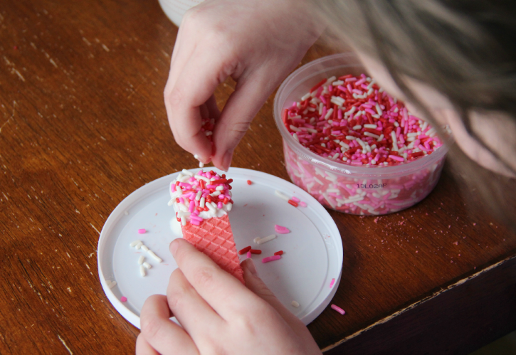 adding sprinkles to the top of a wafer cookie