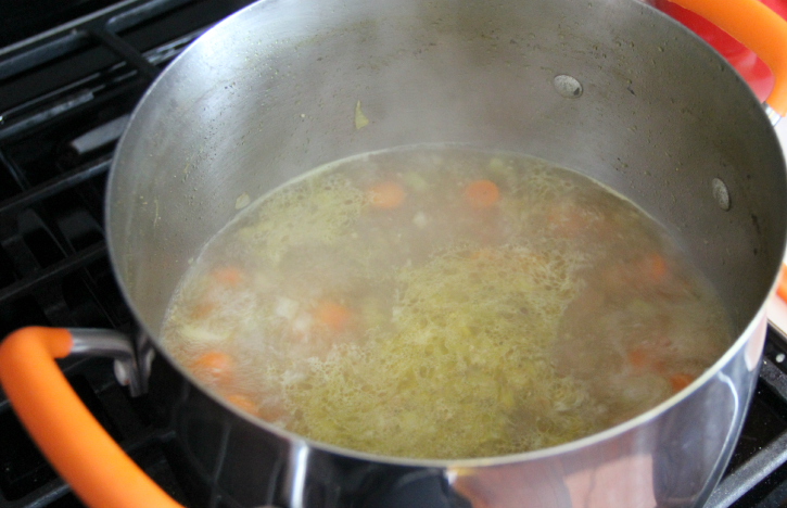 Broth and chopped vegetables in a soup pot