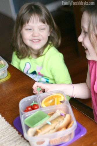 Two children sitting at a table with lunch boxes