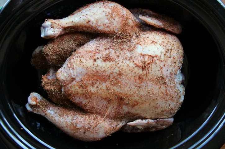 How to Roast a Whole Chicken in the Crockpot - Raw chicken in slow cooker with dry rub 