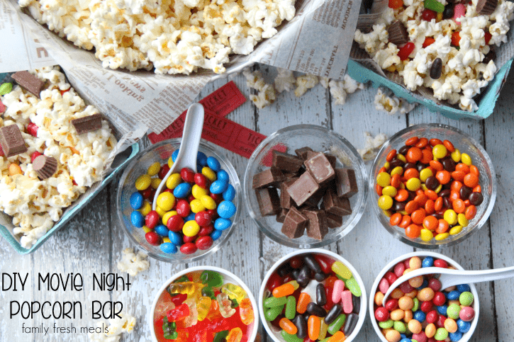 Bowls of Popcorn surrounded by small bowls of different candies