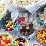 Large bowl of Popcorn surrounded by small bowls of different candies