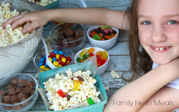 child picking popcorn out of big bowl, smiling