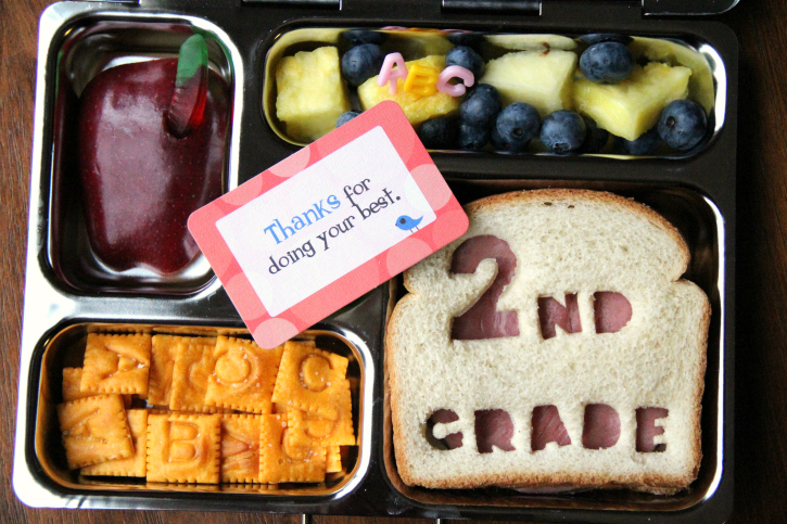 Sandwich, fresh fruit, apple with gummy worm and some cheese crackers.