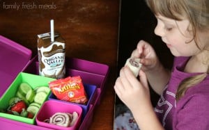 child sitting at a table with a lunchbox