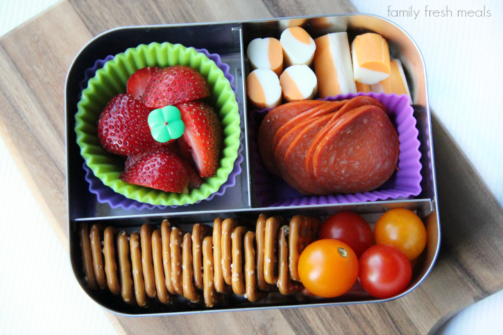 School Lunch Pretzels, pepperoni, cheese, tomatoes and strawberries packed in a lunch box